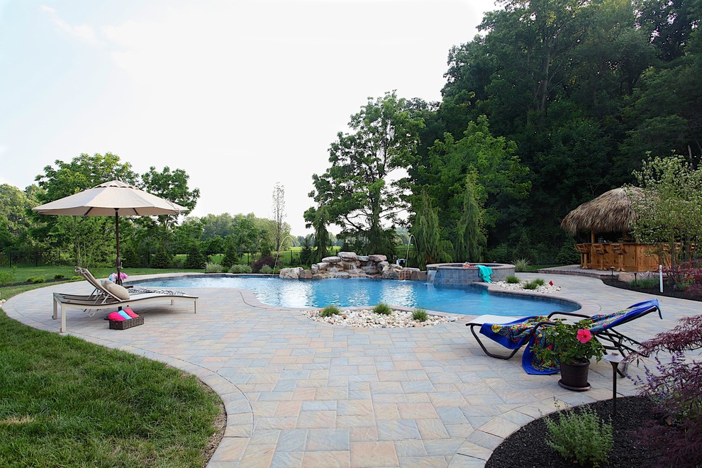 Imagen de casa de la piscina y piscina tradicional de tamaño medio a medida en patio trasero con adoquines de hormigón