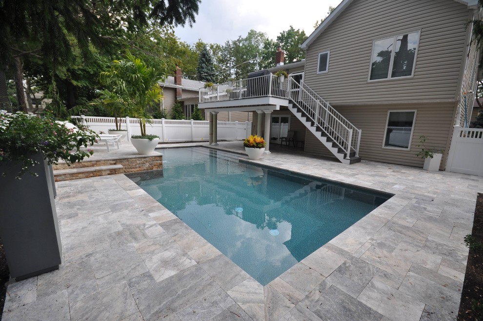 Modelo de piscina alargada tradicional renovada grande rectangular en patio con suelo de baldosas