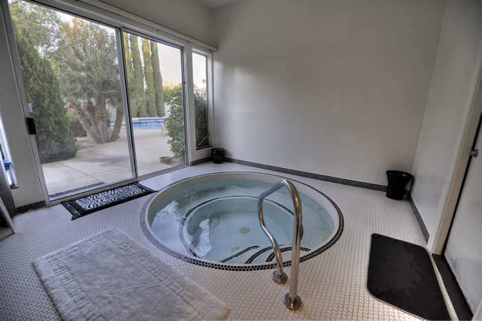 Immagine di un'ampia piscina coperta monocorsia chic rotonda con una vasca idromassaggio e piastrelle