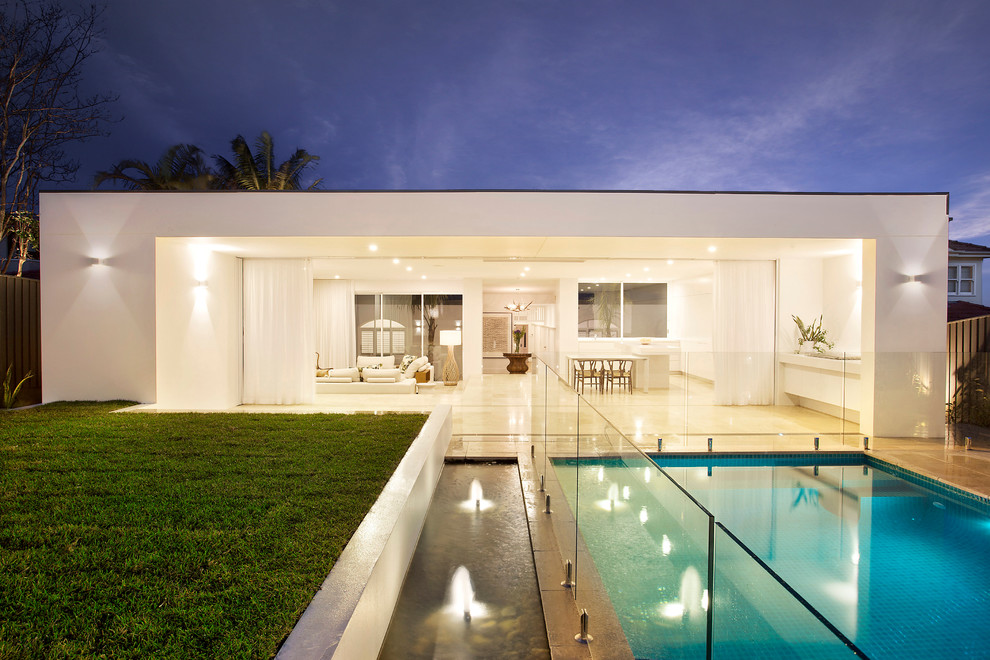 Moderner Pool hinter dem Haus in rechteckiger Form mit Natursteinplatten und Wasserspiel in Sydney