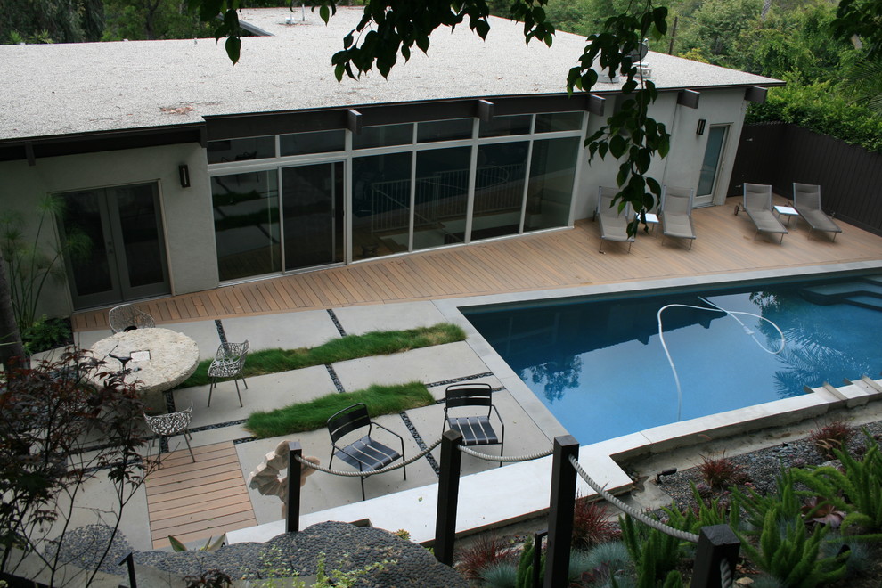 На фото: спортивный, прямоугольный бассейн среднего размера на заднем дворе в современном стиле с настилом