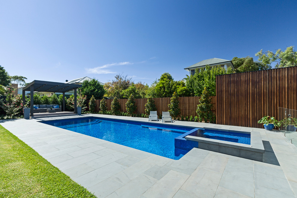 Cette image montre une grande piscine arrière design rectangle avec des pavés en pierre naturelle.