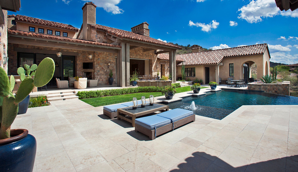 Esempio di una grande piscina a sfioro infinito american style personalizzata dietro casa con fontane e lastre di cemento