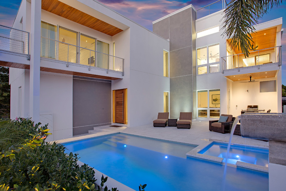 Diseño de piscina con fuente natural actual de tamaño medio rectangular en patio trasero con adoquines de hormigón