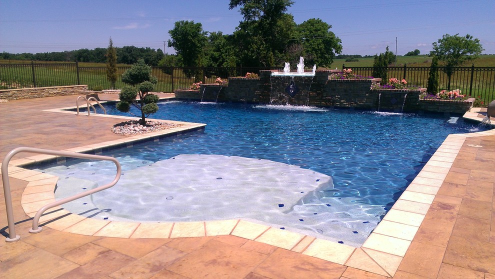 Modelo de piscina con tobogán natural clásica grande en forma de L en patio trasero con adoquines de hormigón