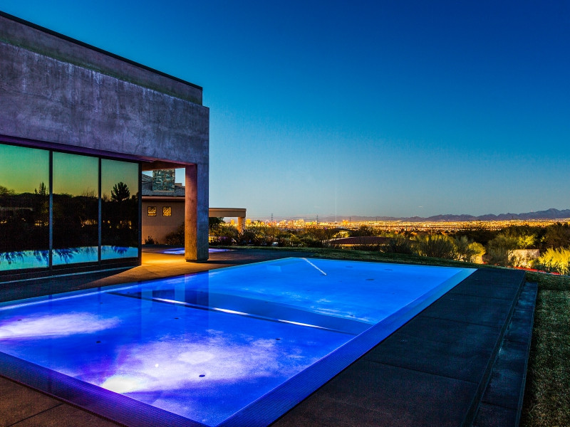 Imagen de piscina infinita moderna grande rectangular en patio trasero con losas de hormigón