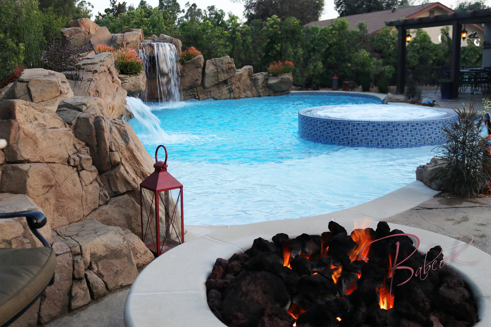 Esempio di una piscina naturale american style personalizzata dietro casa e di medie dimensioni con fontane e pavimentazioni in cemento