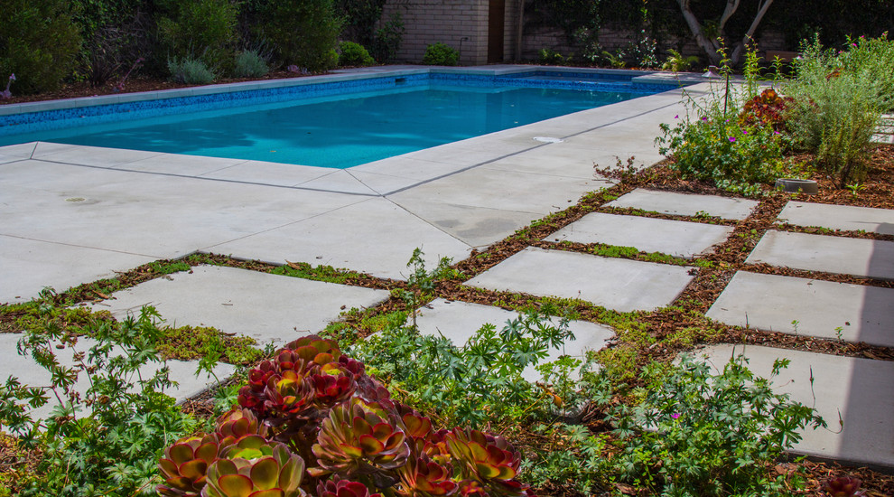 Ejemplo de piscinas y jacuzzis alargados retro de tamaño medio rectangulares en patio trasero con losas de hormigón