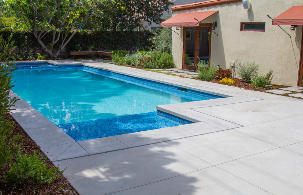 Diseño de piscinas y jacuzzis alargados actuales de tamaño medio rectangulares en patio trasero con losas de hormigón