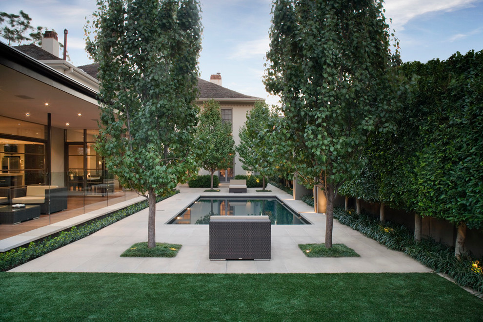 На фото: прямоугольный бассейн на заднем дворе в современном стиле с мощением тротуарной плиткой с