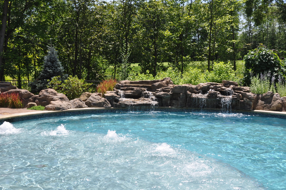 Large rustic back custom shaped natural hot tub in Cleveland with concrete paving.