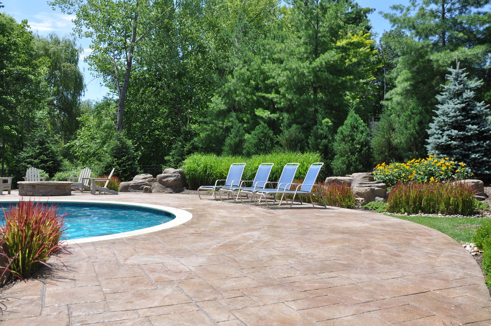 Inspiration for a large rustic back custom shaped natural hot tub in Cleveland with concrete paving.
