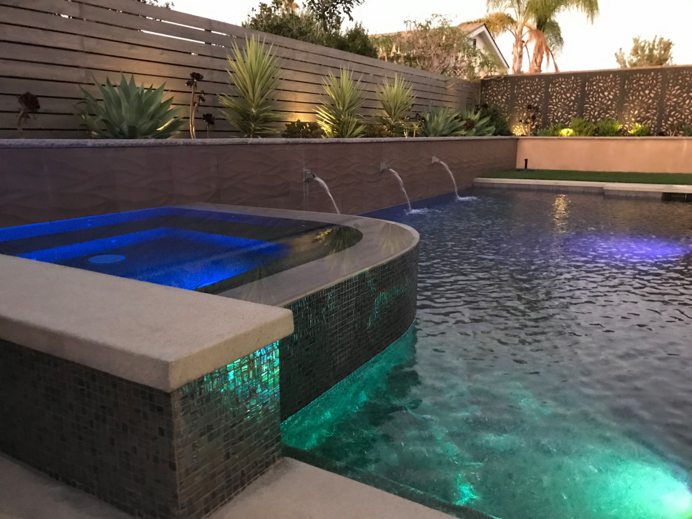 Foto de piscina infinita actual de tamaño medio rectangular en patio trasero con paisajismo de piscina y adoquines de piedra natural