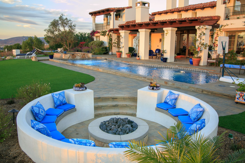 Ejemplo de piscina alargada mediterránea grande rectangular en patio trasero con paisajismo de piscina y adoquines de hormigón