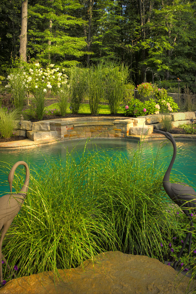 Inspiration for a medium sized traditional side custom shaped natural swimming pool in Detroit with a water feature and brick paving.