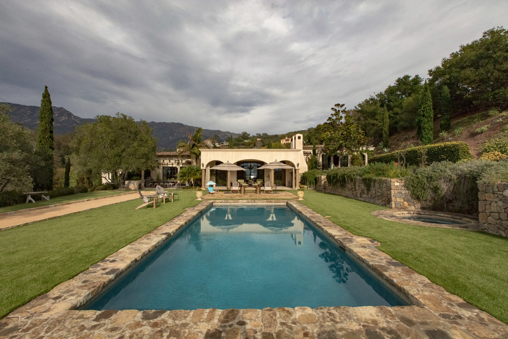 Modelo de piscinas y jacuzzis alargados mediterráneos grandes rectangulares en patio trasero con adoquines de piedra natural