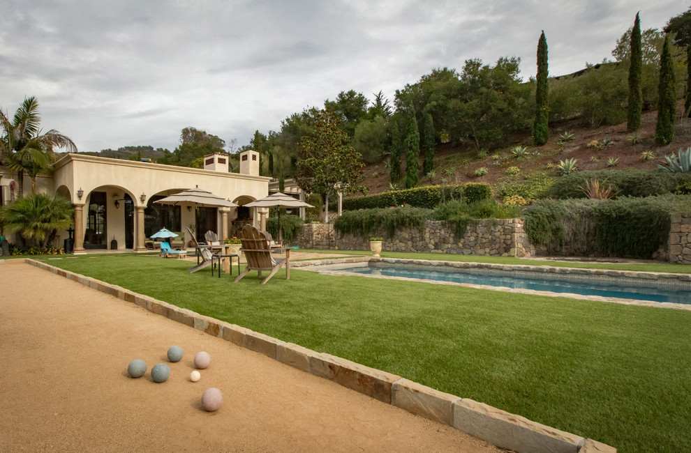 Foto de piscina mediterránea grande rectangular en patio trasero con adoquines de piedra natural