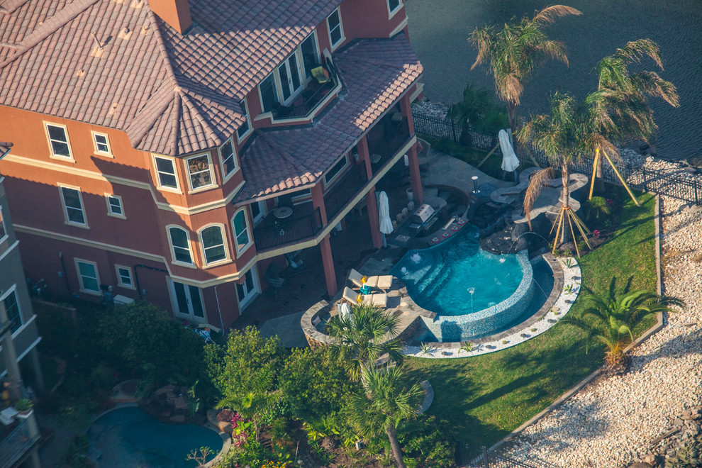 Foto di una piscina a sfioro infinito tropicale personalizzata dietro casa