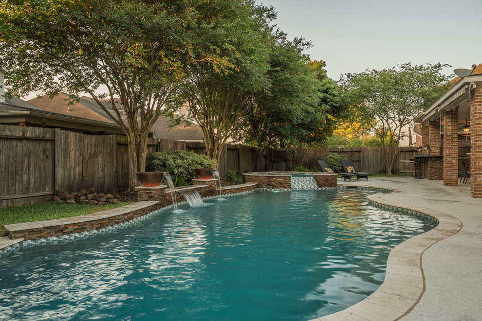 Immagine di una piscina design personalizzata di medie dimensioni e dietro casa con fontane e piastrelle