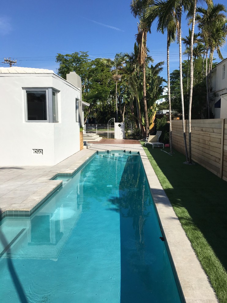 Foto de piscina alargada minimalista grande rectangular en patio trasero con suelo de baldosas