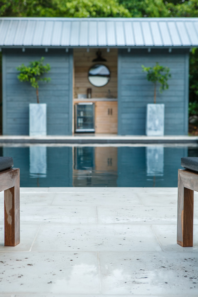 Diseño de casa de la piscina y piscina alargada tropical rectangular en patio trasero con adoquines de hormigón