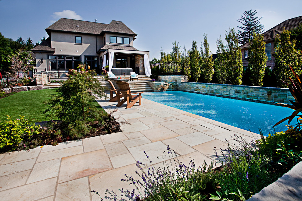 Diseño de piscina tradicional rectangular en patio trasero con adoquines de piedra natural