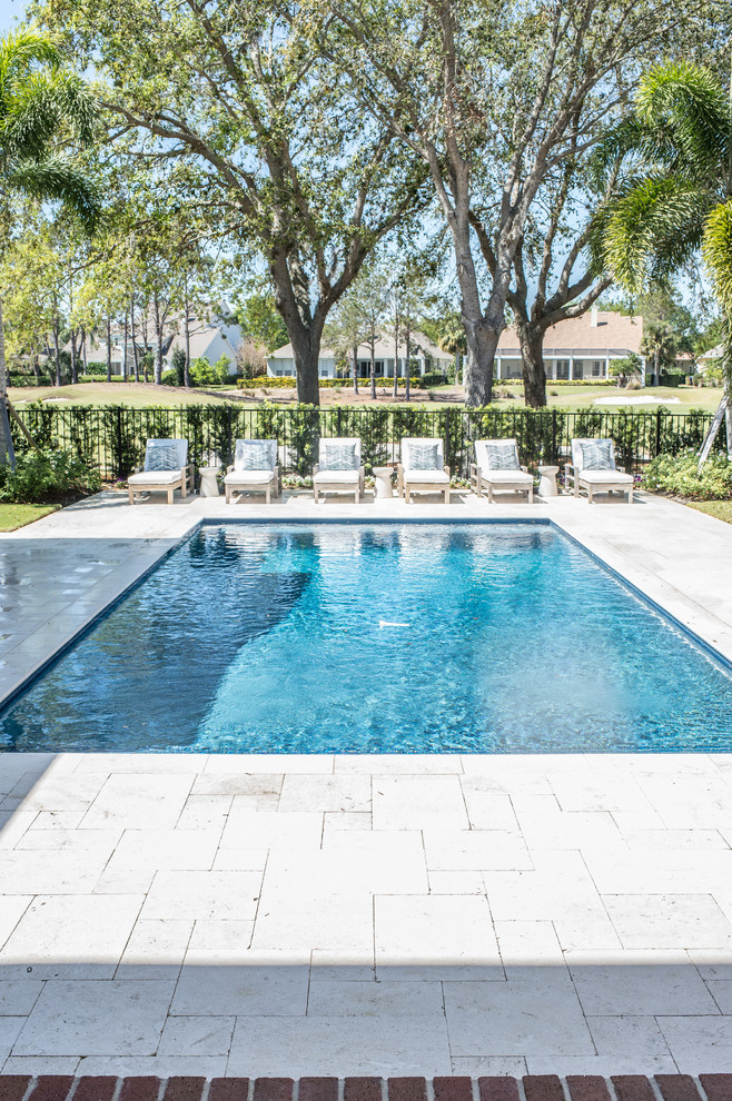 Modelo de piscina alargada, clásica, de tamaño medio, rectangular, en patio trasero, con adoquines de hormigón