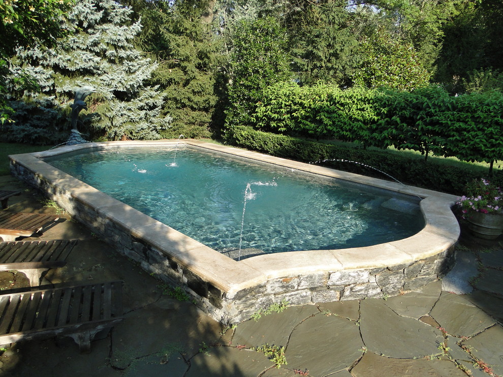 This is an example of a small traditional back custom shaped swimming pool in Philadelphia with a water feature and natural stone paving.