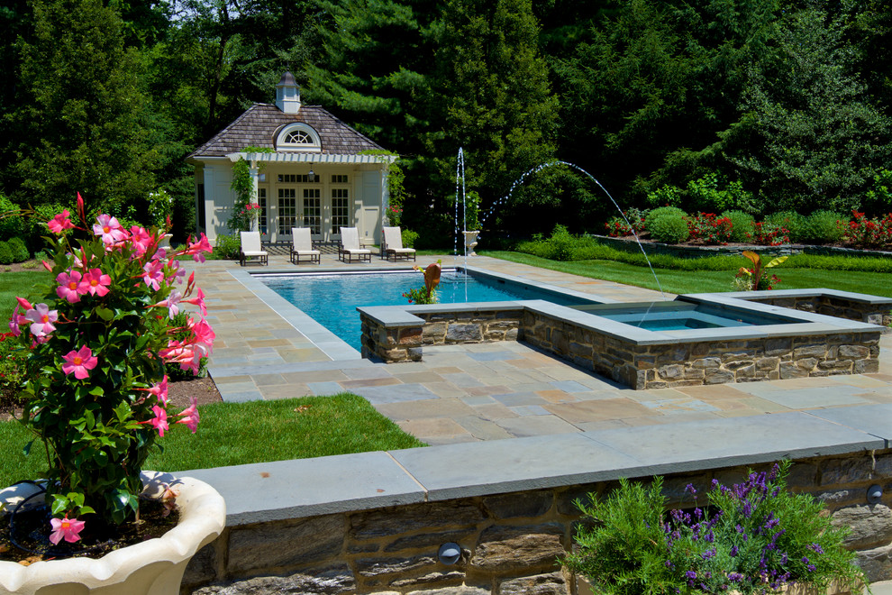 Esempio di una grande piscina monocorsia tradizionale rettangolare dietro casa con fontane e pavimentazioni in pietra naturale