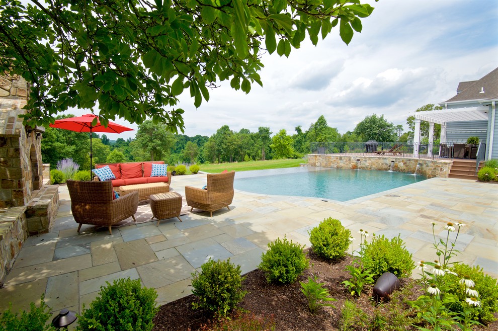 Modelo de piscina con fuente infinita clásica grande rectangular en patio trasero con adoquines de piedra natural