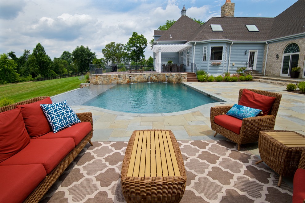 Foto di una grande piscina a sfioro infinito tradizionale rettangolare dietro casa con fontane e pavimentazioni in pietra naturale