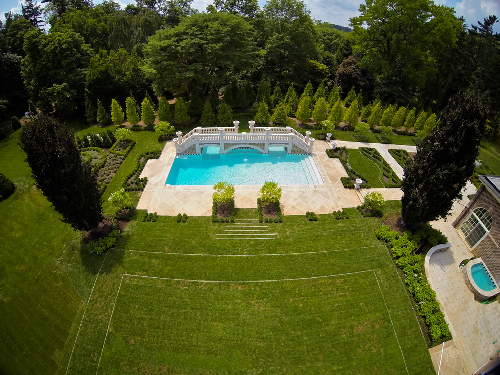 Inspiration pour une très grande piscine arrière traditionnelle rectangle avec un point d'eau et une terrasse en bois.