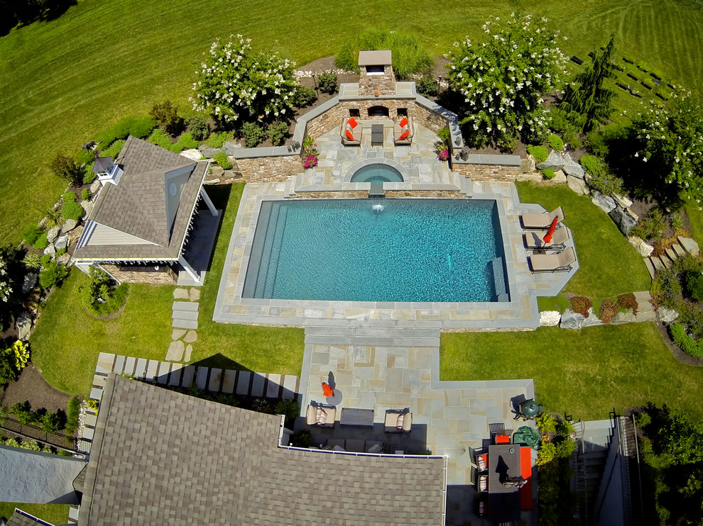 Exemple d'une grande piscine arrière chic rectangle avec un bain bouillonnant et une terrasse en bois.