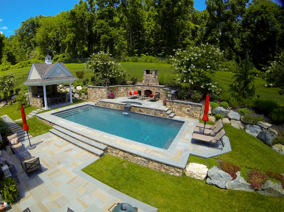 Immagine di una grande piscina tradizionale rettangolare dietro casa con una vasca idromassaggio e pedane