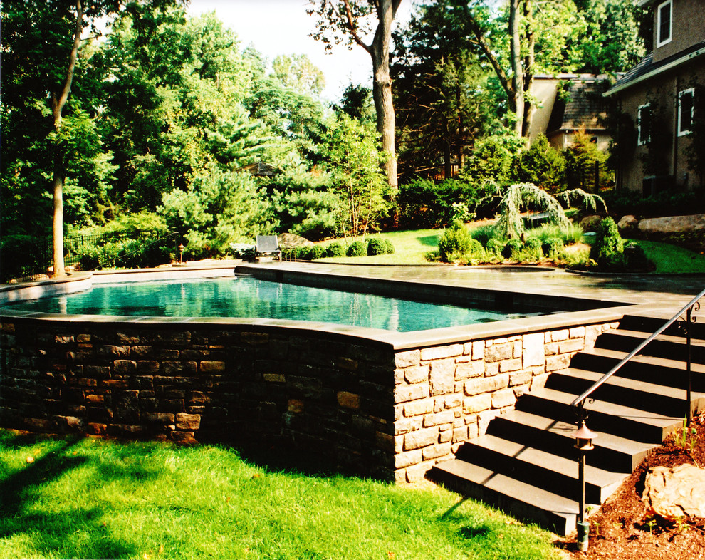 Diseño de piscina tradicional grande a medida en patio trasero con adoquines de piedra natural