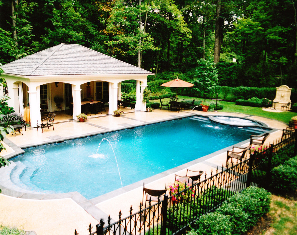 Bild på en stor vintage anpassad pool på baksidan av huset, med poolhus och betongplatta