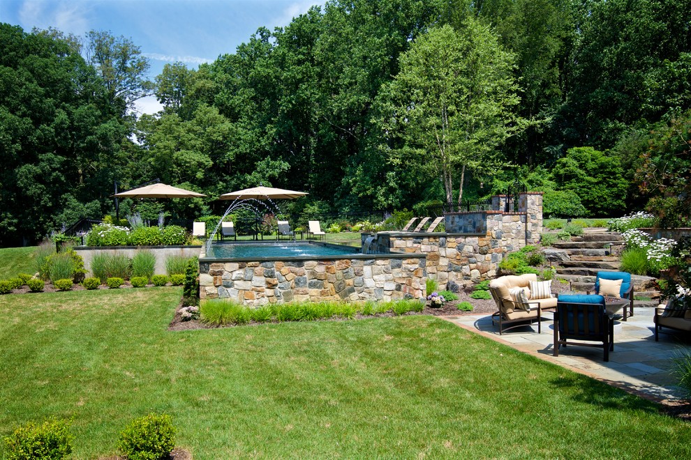 Diseño de piscina con fuente alargada clásica de tamaño medio rectangular en patio trasero con adoquines de piedra natural