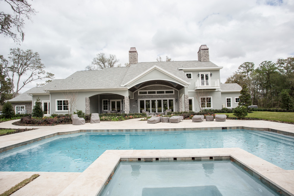 Esempio di una grande piscina monocorsia chic rettangolare dietro casa con una vasca idromassaggio e lastre di cemento