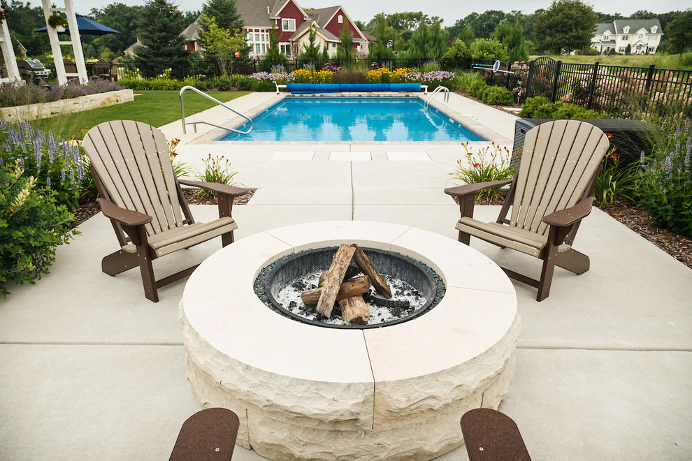 Diseño de piscina clásica de tamaño medio rectangular en patio trasero con losas de hormigón