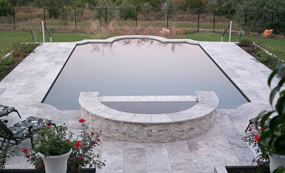 This is an example of a large classic back rectangular hot tub in Austin with natural stone paving.