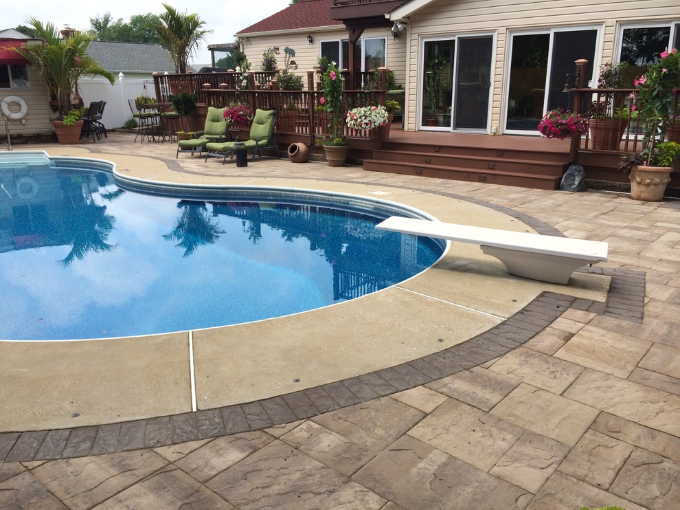 Foto de piscina alargada tradicional de tamaño medio tipo riñón en patio trasero con adoquines de piedra natural