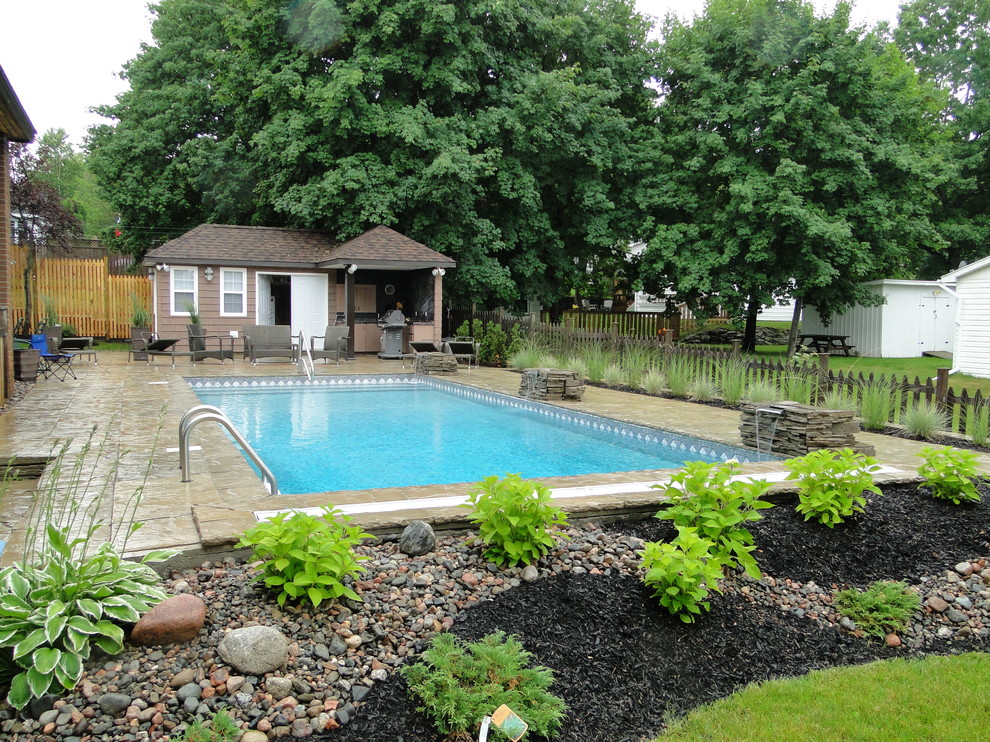 Foto di una piscina classica rettangolare di medie dimensioni e dietro casa con fontane e pavimentazioni in cemento