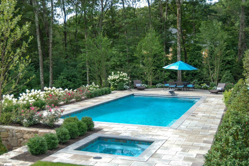Modelo de piscinas y jacuzzis clásicos grandes rectangulares en patio trasero con adoquines de piedra natural