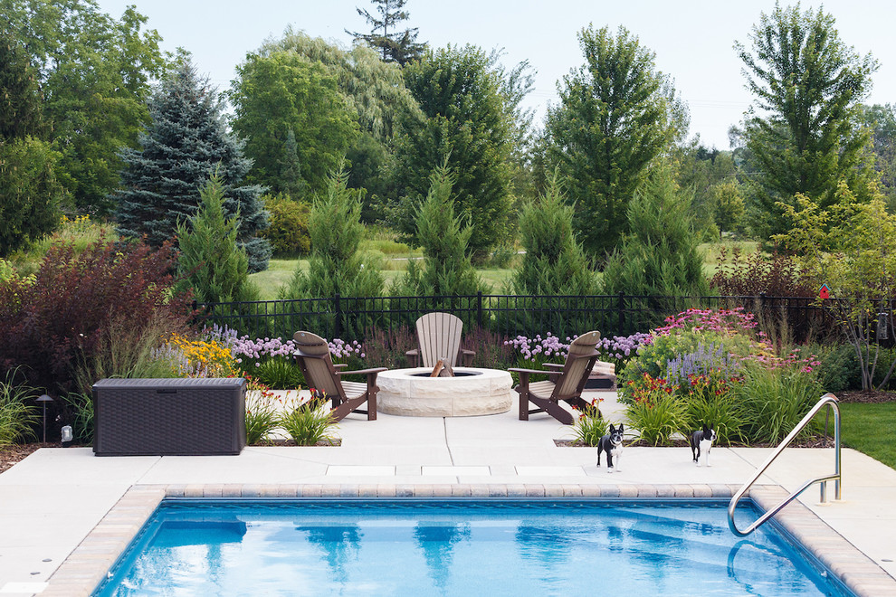 Imagen de piscina tradicional de tamaño medio rectangular en patio trasero con losas de hormigón
