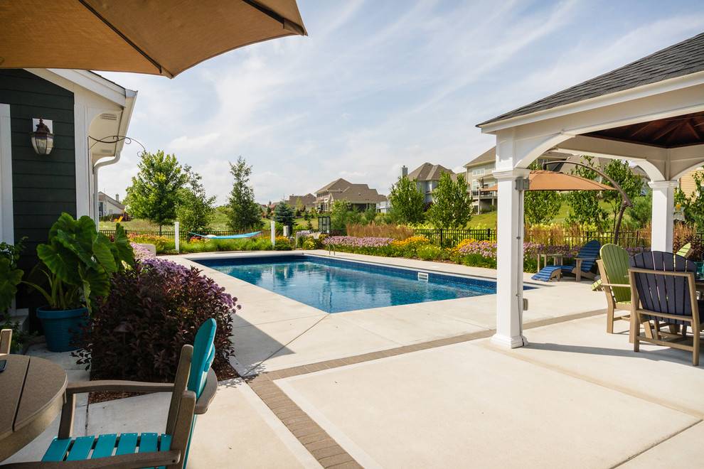 Imagen de casa de la piscina y piscina clásica de tamaño medio rectangular en patio trasero con losas de hormigón