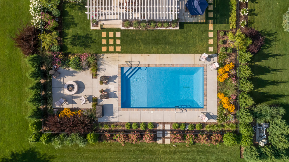 Ejemplo de piscina clásica renovada grande rectangular en patio trasero con losas de hormigón