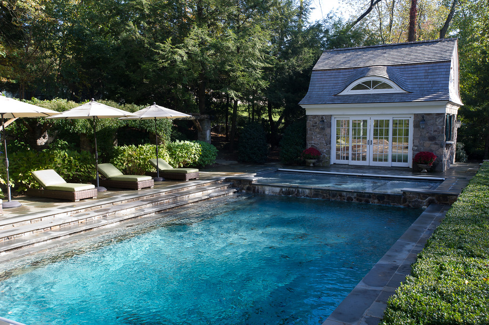Ejemplo de casa de la piscina y piscina clásica rectangular en patio trasero con adoquines de piedra natural