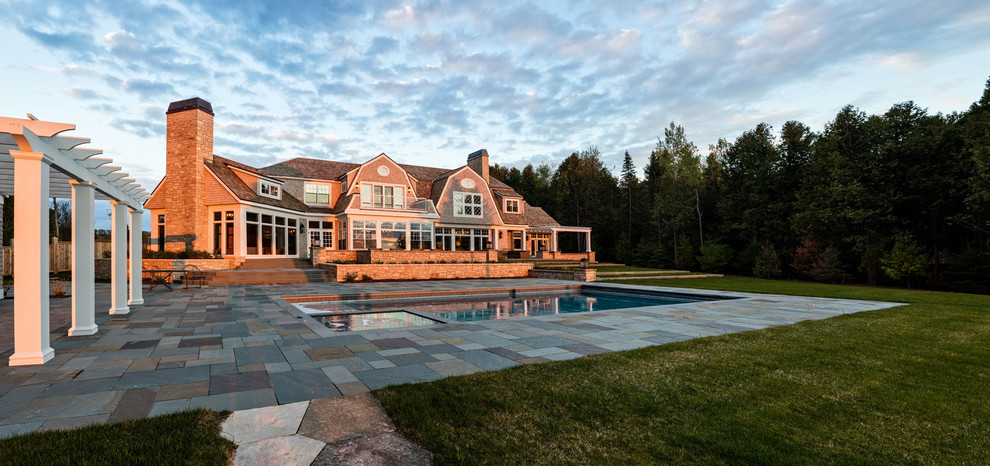 Imagen de piscina con fuente alargada tradicional grande rectangular en patio trasero con adoquines de piedra natural