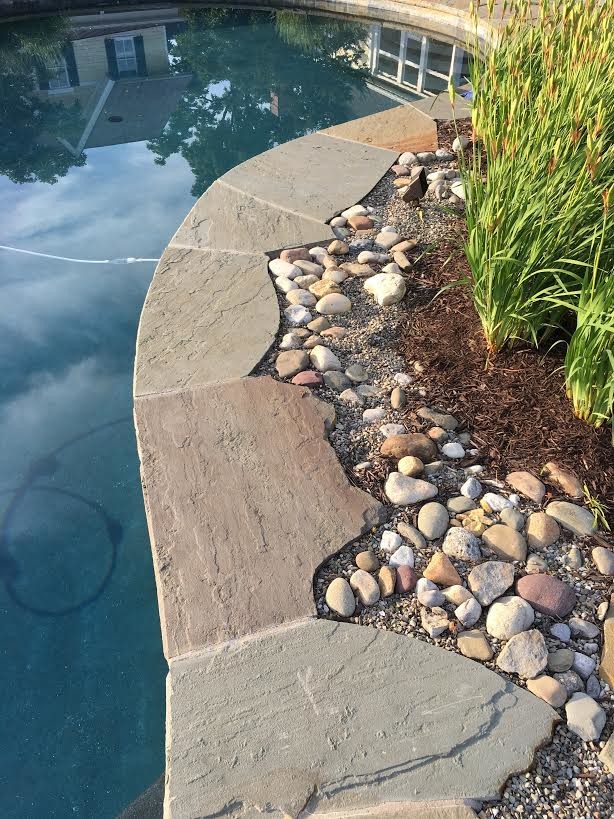 Diseño de piscina tradicional de tamaño medio a medida en patio trasero con adoquines de piedra natural