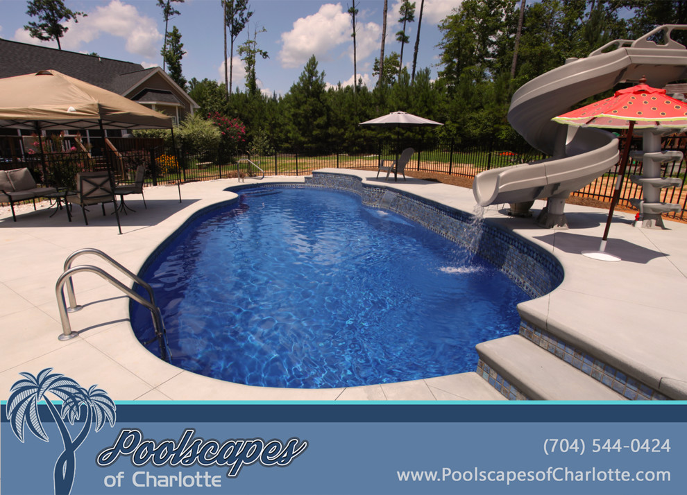 Design ideas for a large classic back custom shaped swimming pool in Charlotte with a water slide and stamped concrete.